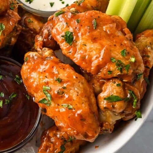 close up shot of two ninja foodi chicken wings topped with parsley.