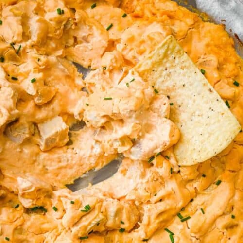 close up shot of buffalo chicken dip with a chip scooping it out.