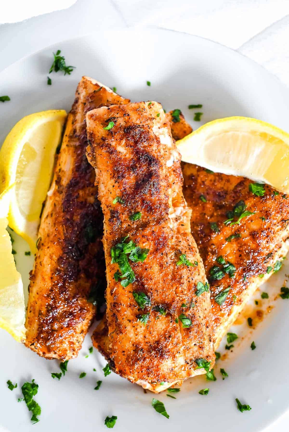 air fryer mahi mahi on a dish with parsley and lemon
